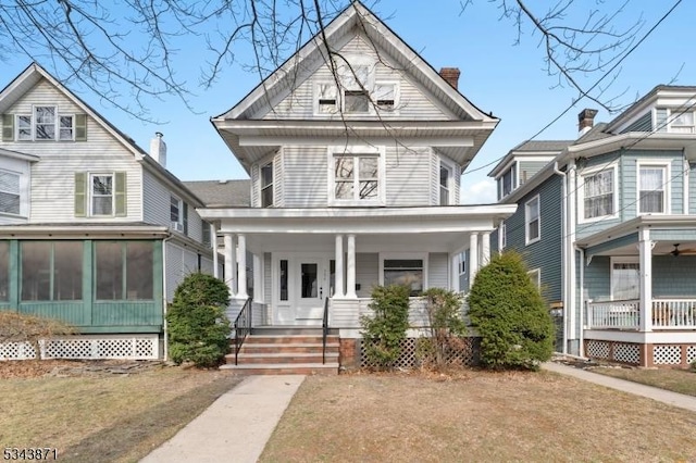 view of front facade featuring a porch, a chimney, and a sunroom