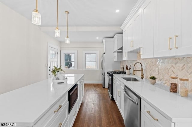 kitchen with a sink, under cabinet range hood, stainless steel appliances, light countertops, and decorative backsplash