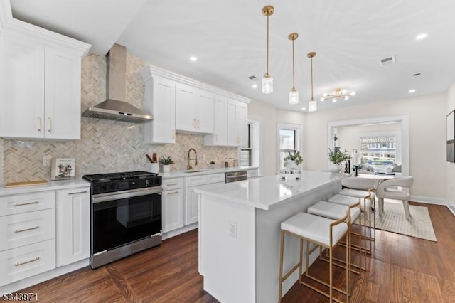 kitchen with visible vents, light countertops, gas range oven, decorative backsplash, and wall chimney exhaust hood