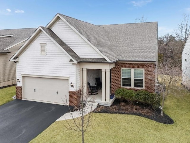 traditional home with brick siding, a front yard, roof with shingles, and driveway