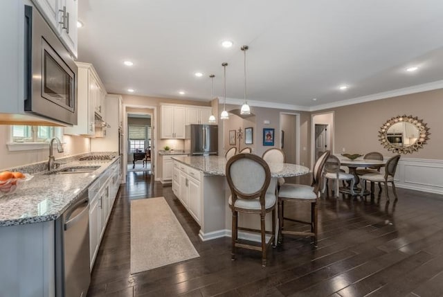 kitchen featuring dark wood-type flooring, a kitchen island, appliances with stainless steel finishes, and a breakfast bar