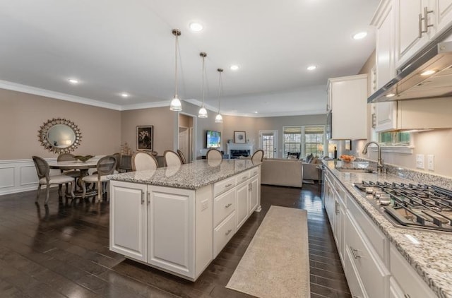 kitchen featuring a sink, a kitchen island, open floor plan, white cabinetry, and stainless steel gas stovetop