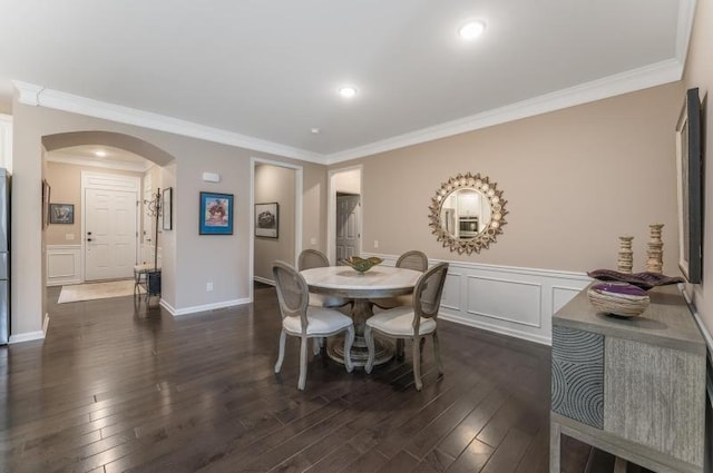 dining space featuring arched walkways, dark wood-type flooring, ornamental molding, and a decorative wall