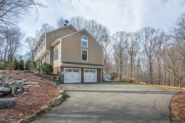 view of home's exterior with stairs, aphalt driveway, and an attached garage