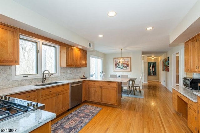 kitchen with a sink, tasteful backsplash, light wood-style floors, appliances with stainless steel finishes, and a peninsula