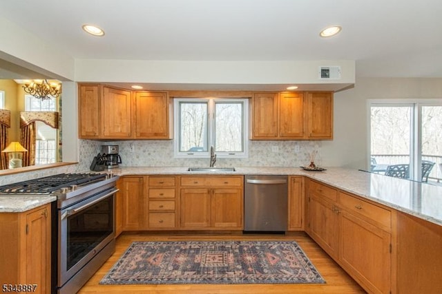 kitchen featuring visible vents, an inviting chandelier, a peninsula, a sink, and appliances with stainless steel finishes