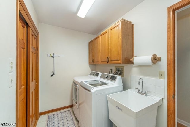 washroom featuring washer and clothes dryer, cabinet space, baseboards, and a sink