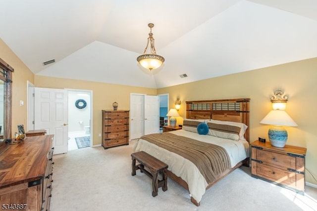 bedroom featuring visible vents, lofted ceiling, light colored carpet, and connected bathroom