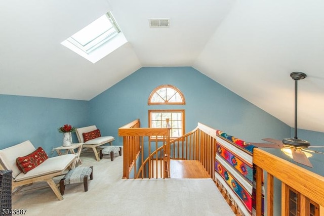 interior space featuring an upstairs landing, visible vents, and vaulted ceiling with skylight