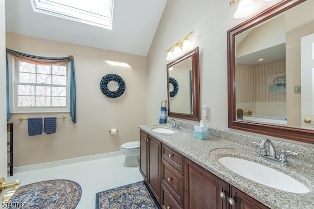 bathroom with a sink, lofted ceiling with skylight, toilet, and double vanity