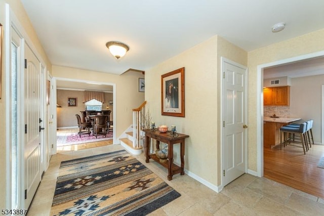 hallway featuring visible vents, baseboards, and stairs