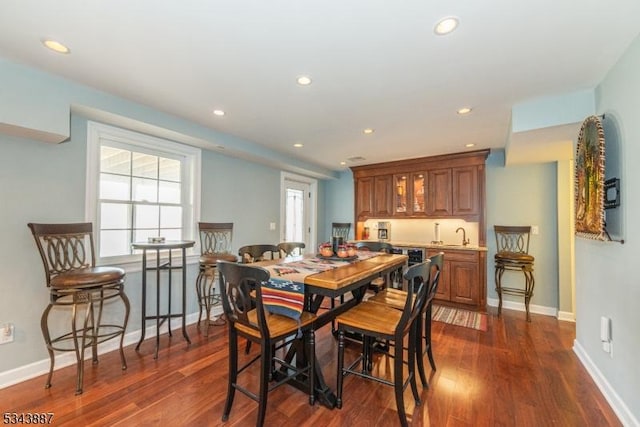 dining space with recessed lighting, wet bar, dark wood-type flooring, and baseboards