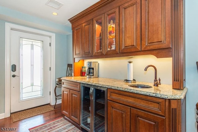 kitchen featuring beverage cooler, visible vents, brown cabinets, and a sink