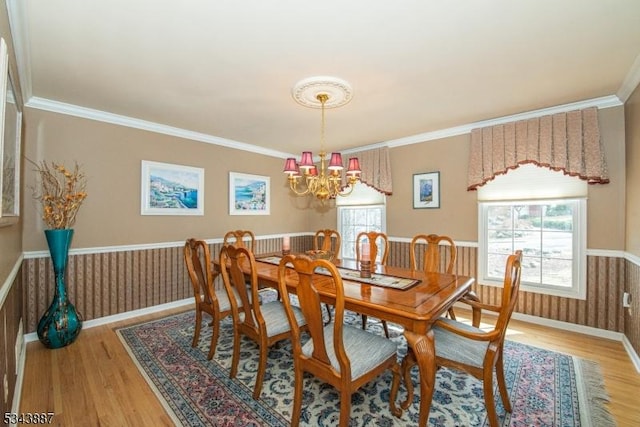 dining space with crown molding, an inviting chandelier, and wood finished floors