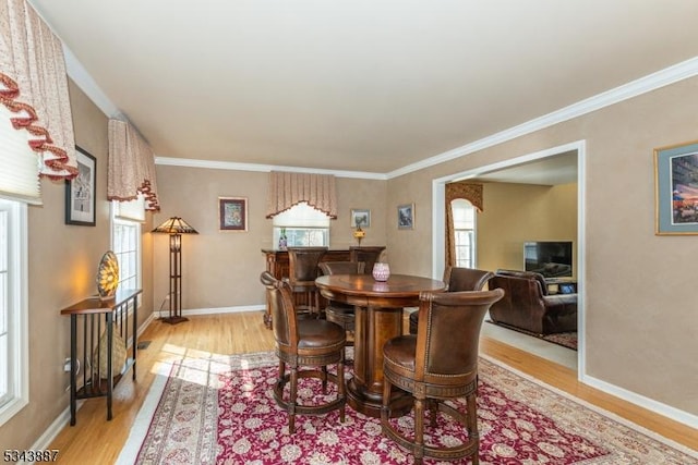 dining area featuring light wood-type flooring, baseboards, and ornamental molding