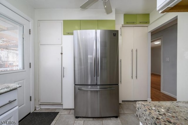 kitchen featuring light tile patterned floors, freestanding refrigerator, ceiling fan, and light stone countertops