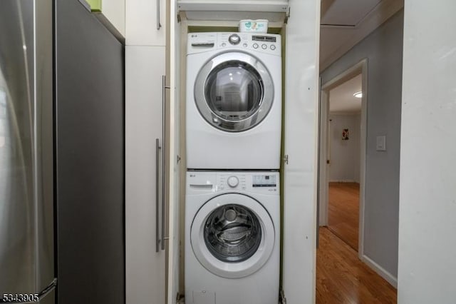 laundry area with laundry area, wood finished floors, and stacked washing maching and dryer