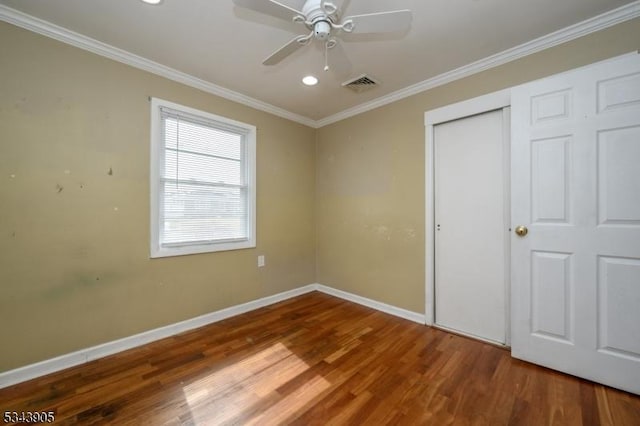 unfurnished bedroom featuring visible vents, wood finished floors, baseboards, and ornamental molding