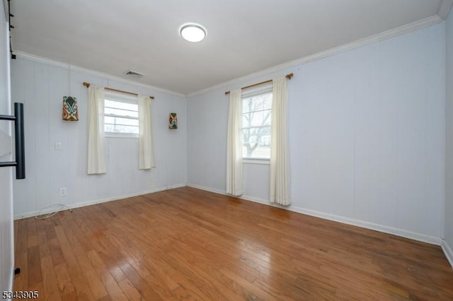 empty room with visible vents, crown molding, and wood-type flooring