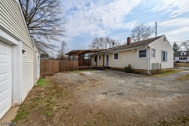 rear view of house with a garage, a chimney, and fence