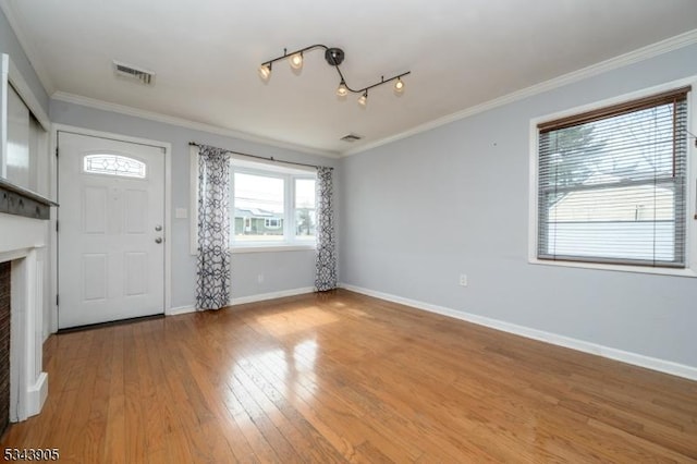 foyer entrance featuring visible vents, light wood-style flooring, baseboards, and ornamental molding