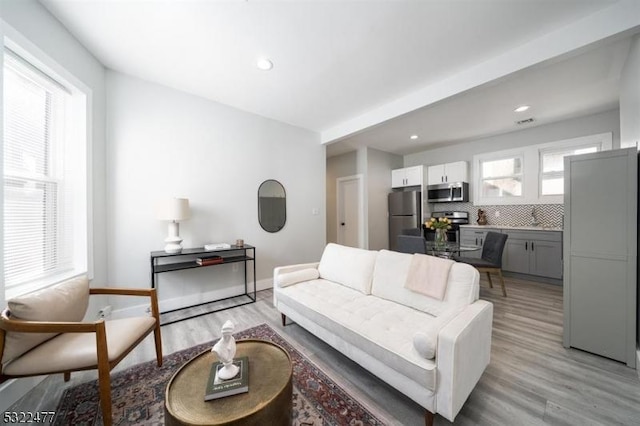 living room with recessed lighting, light wood-type flooring, and baseboards