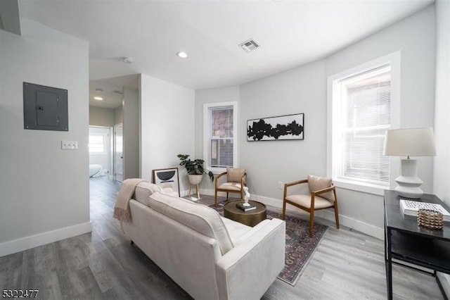 living room featuring visible vents, baseboards, electric panel, recessed lighting, and wood finished floors