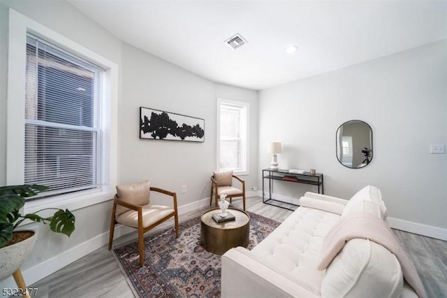 living area with visible vents, baseboards, and wood finished floors