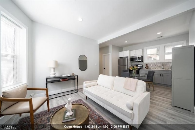 living area featuring recessed lighting, light wood-type flooring, and baseboards