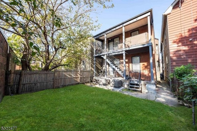 rear view of house with stairway, a balcony, fence, a yard, and central air condition unit