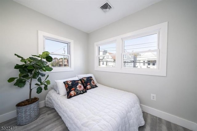 bedroom featuring wood finished floors, visible vents, and baseboards