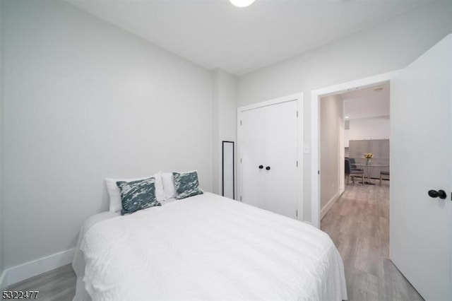 bedroom featuring light wood finished floors and baseboards