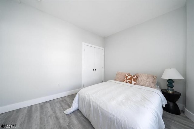 bedroom with a closet, baseboards, and wood finished floors