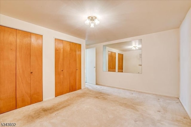 unfurnished bedroom with two closets and carpet