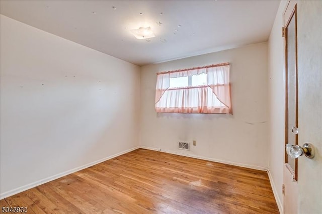 unfurnished room with wood finished floors, visible vents, and baseboards