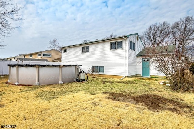 back of property with a covered pool and a yard