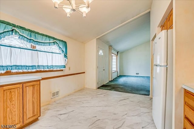 kitchen featuring visible vents, vaulted ceiling, freestanding refrigerator, a notable chandelier, and marble finish floor