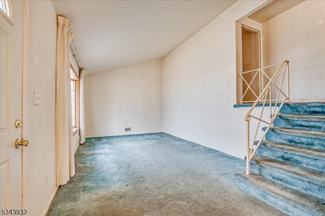 unfurnished room with lofted ceiling, stairway, and carpet floors