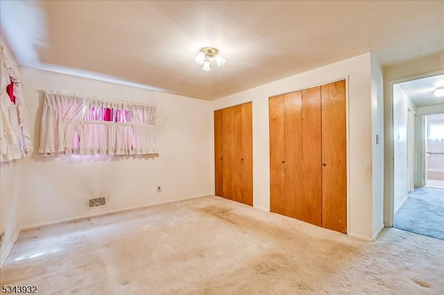 unfurnished bedroom with two closets and carpet