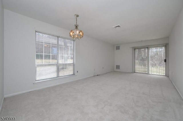 empty room featuring visible vents, carpet floors, and an inviting chandelier