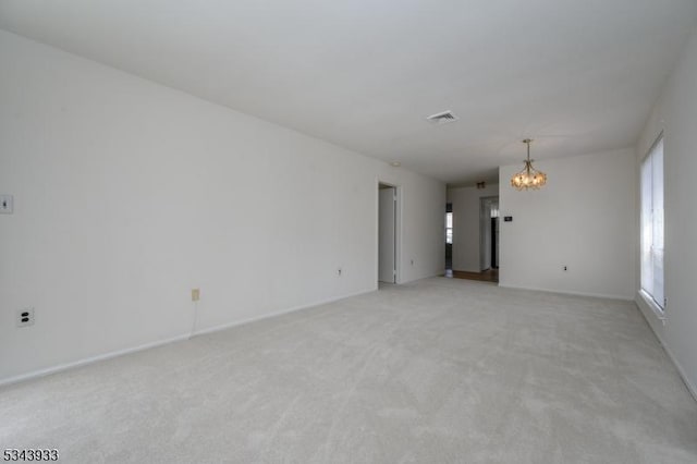 empty room featuring a notable chandelier, light colored carpet, visible vents, and baseboards