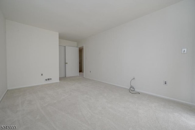 empty room featuring light colored carpet, visible vents, and baseboards