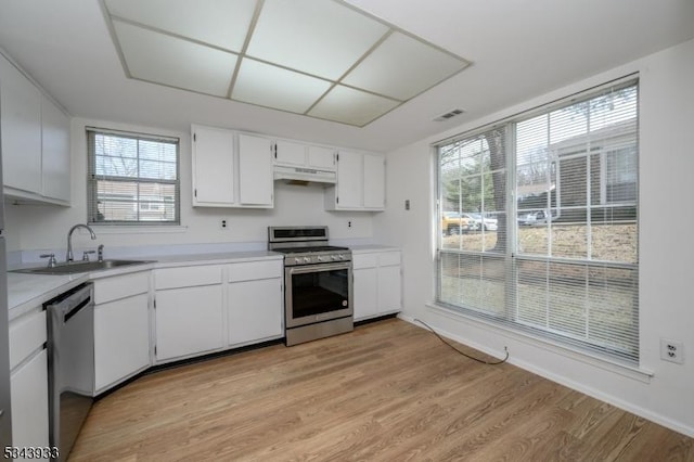 kitchen featuring visible vents, a sink, light countertops, under cabinet range hood, and appliances with stainless steel finishes