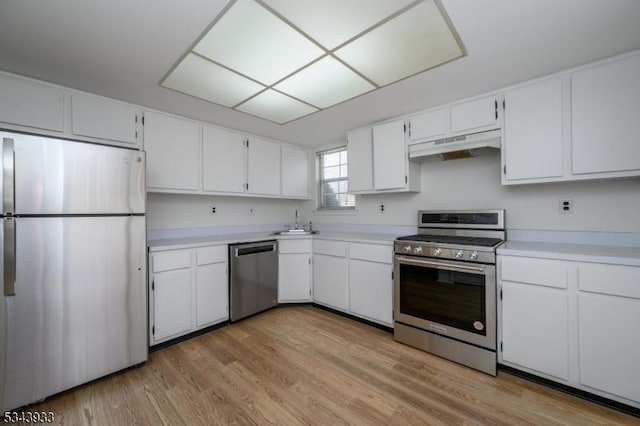 kitchen featuring under cabinet range hood, a sink, stainless steel appliances, white cabinets, and light countertops