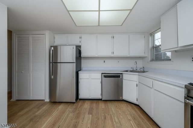 kitchen with light wood-style flooring, a sink, stainless steel appliances, white cabinets, and light countertops