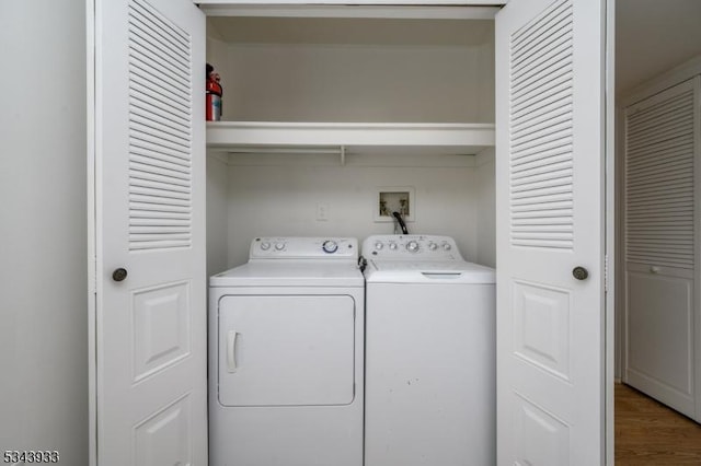 laundry area with laundry area, washing machine and dryer, and wood finished floors