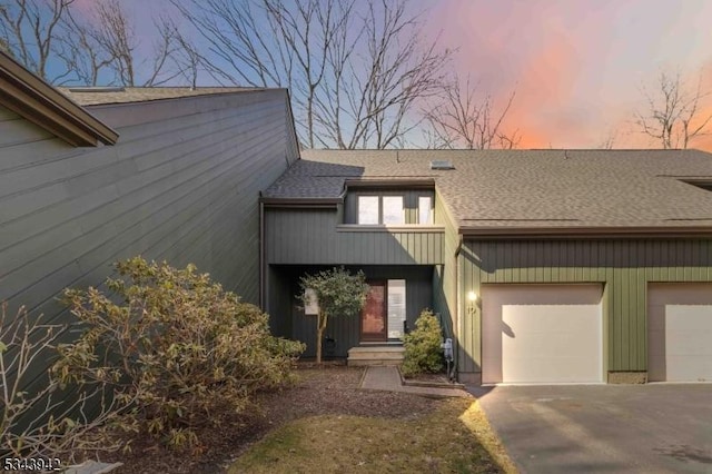 view of front of property with aphalt driveway, an attached garage, and roof with shingles