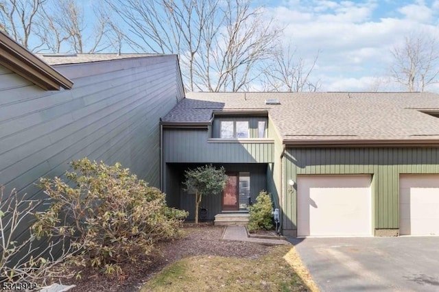 view of front facade featuring a garage, driveway, and a shingled roof