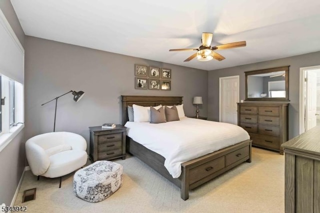 bedroom with baseboards, a ceiling fan, visible vents, and light carpet