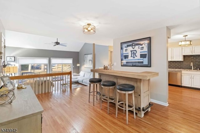 kitchen with tasteful backsplash, dishwasher, light countertops, light wood-style floors, and a sink